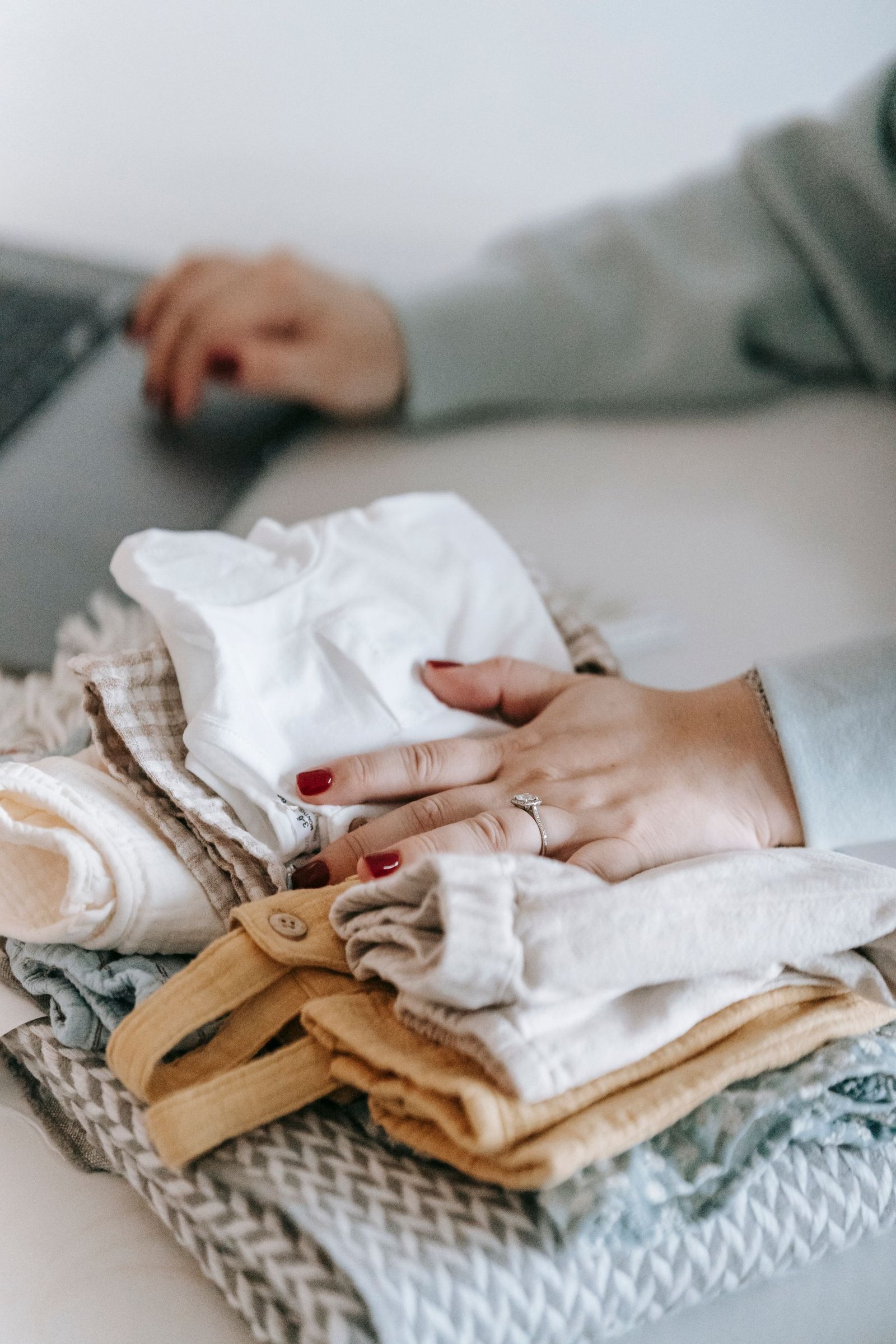 Hands carefully arranging a stack of folded clothes