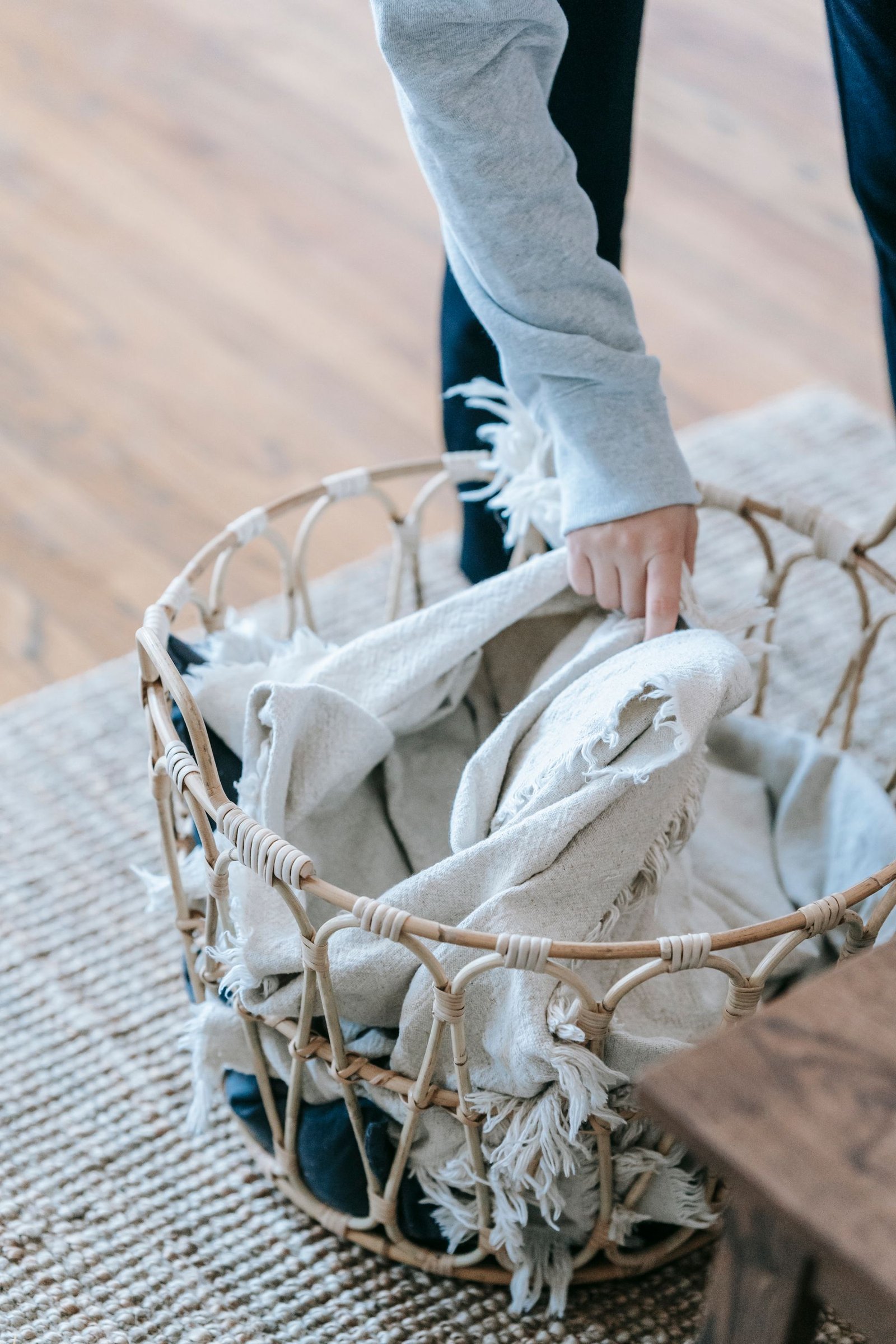 Hand placing light-coloured household linen into a woven basket